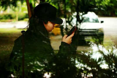 Side view of woman using mobile phone seen through glass window