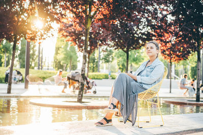 Side view of young woman sitting in park