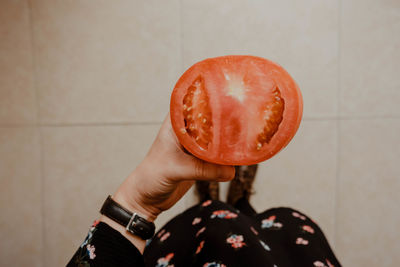 Midsection of woman holding apple against wall