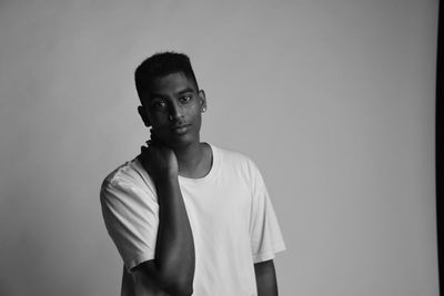 Portrait of young man standing against backdrop