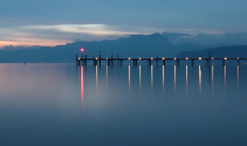 Wooden posts in lake against sky during sunset