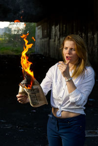 Young woman holding burning newspaper