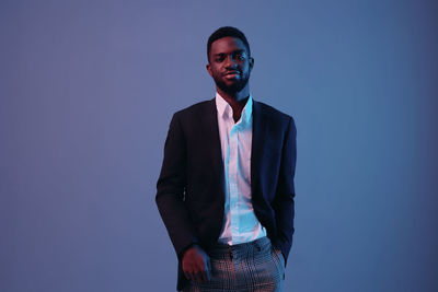 Portrait of young man standing against gray background