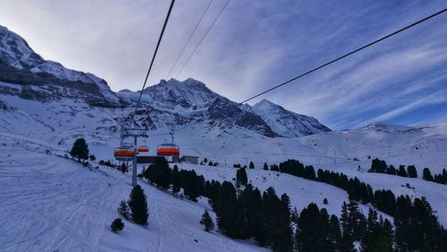 Overhead cable car on snowcapped mountains against sky