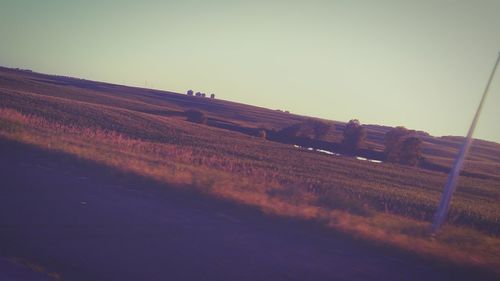 Road amidst field against clear sky