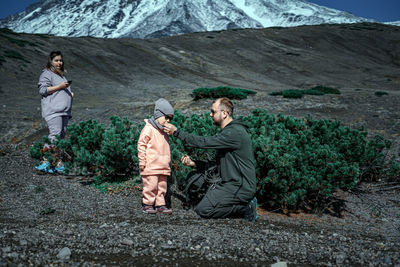 Friends sitting on rock against mountains