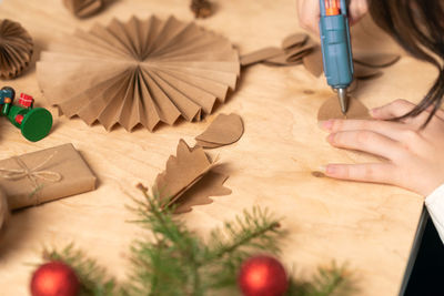 Cropped hand of woman holding christmas decoration on table