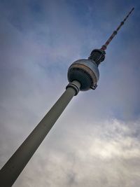 Low angle view of communications tower against cloudy sky