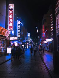 People walking on illuminated street at night