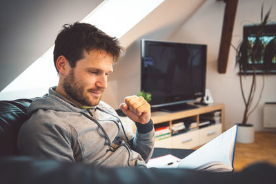 Young man using mobile phone while sitting at home