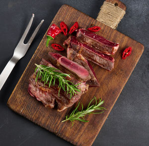 Roasted piece of beef ribeye cut into pieces on a vintage brown chopping board, rare 