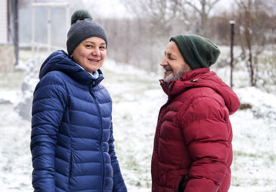 Portrait of mature woman wearing warm clothing standing with father outdoors during winter