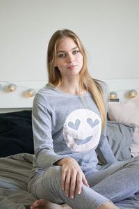 Portrait of woman sitting on bed at home