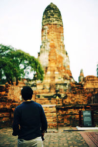 Rear view of man standing against temple and sky