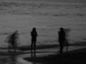 Silhouette people walking on beach