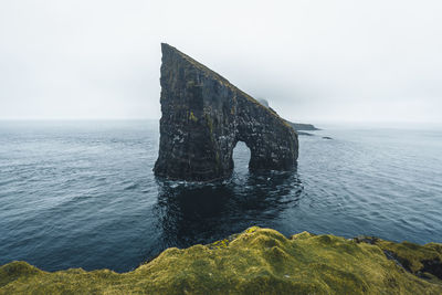 Built structure on rock by sea against sky
