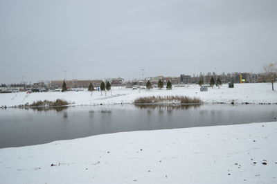 Frozen river in city against sky