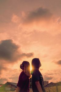 Man and woman standing against orange sky