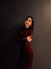 Portrait of young woman standing against black background