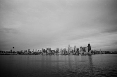 Sea by buildings against sky in city