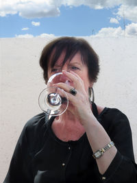 Woman drinking wine while sitting against wall