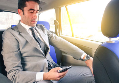 Businessman using phone while traveling in car