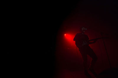 Silhouette man standing against illuminated lamp at night