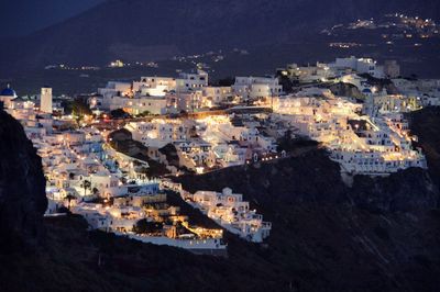 High angle view of illuminated city by sea at night