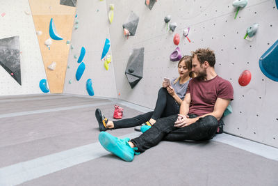 Female showing smart phone to male friend while sitting in gym