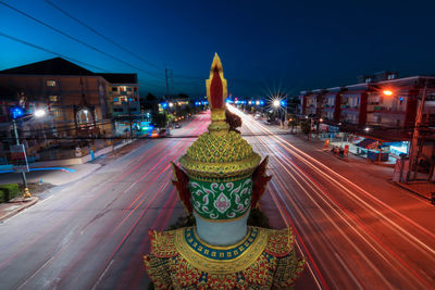 Light trails on street against illuminated buildings in city at night