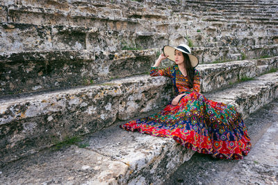 Woman wearing hat sitting on staircase outdoors