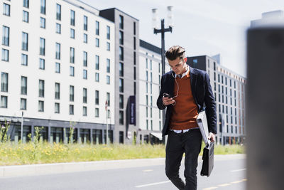 Young man with cell phone and earbuds on the move