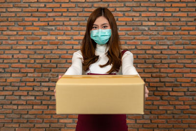 Portrait of a woman standing against brick wall