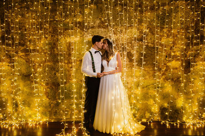 Full length of couple embracing against illuminated lighting