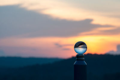 Close-up of light bulb against sky during sunset