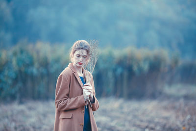 Woman looking at camera while standing on field