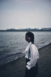 Full length of woman standing on beach against sky