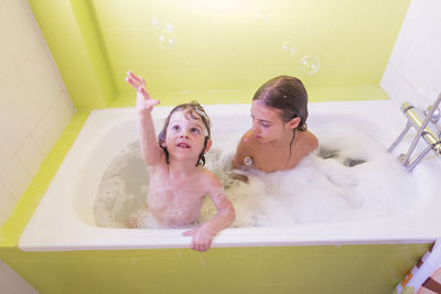 High angle view of siblings playing in bathtub