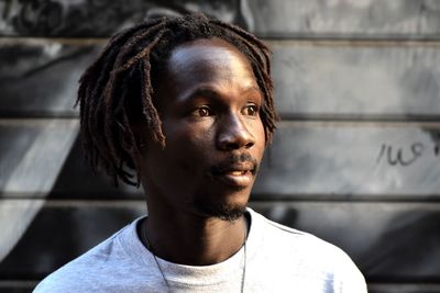 Portrait of young man looking away against wall