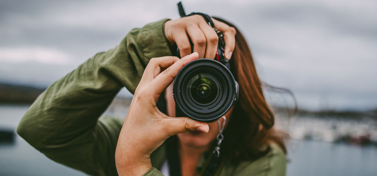 MIDSECTION OF PERSON HOLDING CAMERA WITH REFLECTION