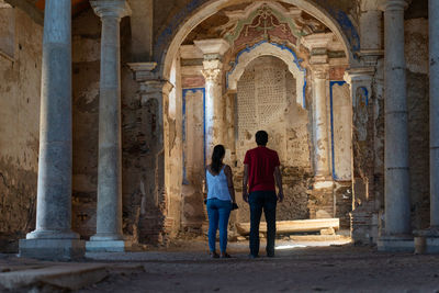 Rear view of people standing at historical building