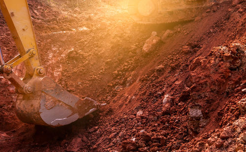 Metal bucket of backhoe digging soil. backhoe working by digging soil at the construction site. 