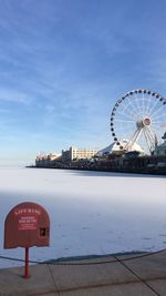 Ferris wheel in city against cloudy sky