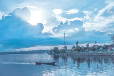 View of sailboats in river against cloudy sky