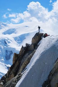 Person standing on top of rocky mountain during winter