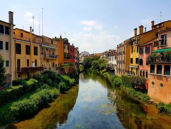 Canal amidst houses against sky in city