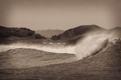 Waves splashing on shore against clear sky