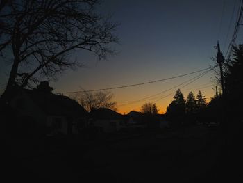 Silhouette trees and buildings against sky at sunset