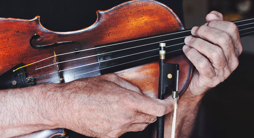 An old violin and a bow in the hands of a violinist. gipsy strings music.