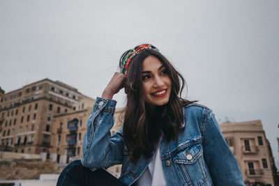 Portrait of smiling young woman against sky